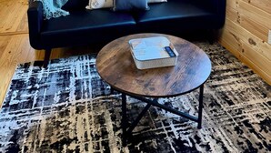 A cozy room with a black sofa, a patterned throw blanket, and a coffee table with a remote control. - Walking Distance to Lakes James with Resort Amenities (Marion)