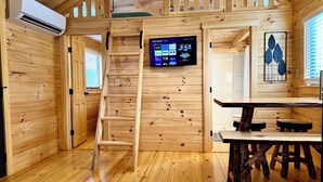 A wooden cabin interior with a wooden ladder, a mounted TV, and a dining table. - Walking Distance to Lakes James with Resort Amenities (Marion)