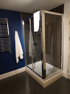 A glass-enclosed shower with a white towel hanging on the wall.