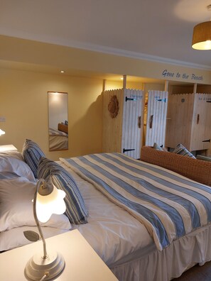 A hotel room with a large bed, two bedside lamps, a mirror, and a sign reading "Gone to the Beach".