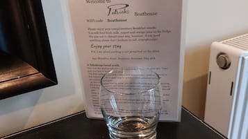 A glass of water on a black table with a welcome sign for 'Patrick's Boathouse' behind it.