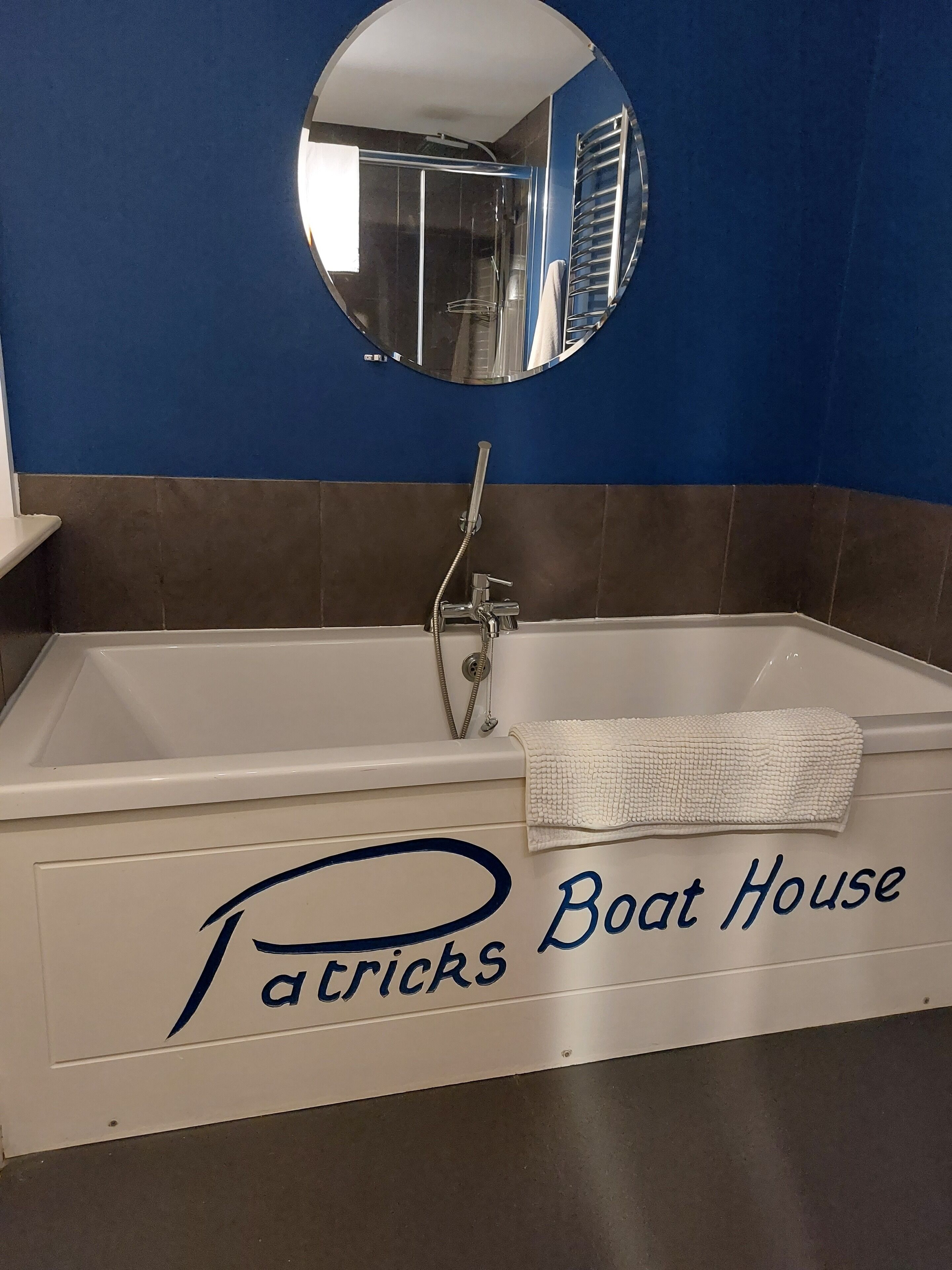 A bathroom with a white bathtub, a towel, and a sign that reads "Patrick's Boat House".