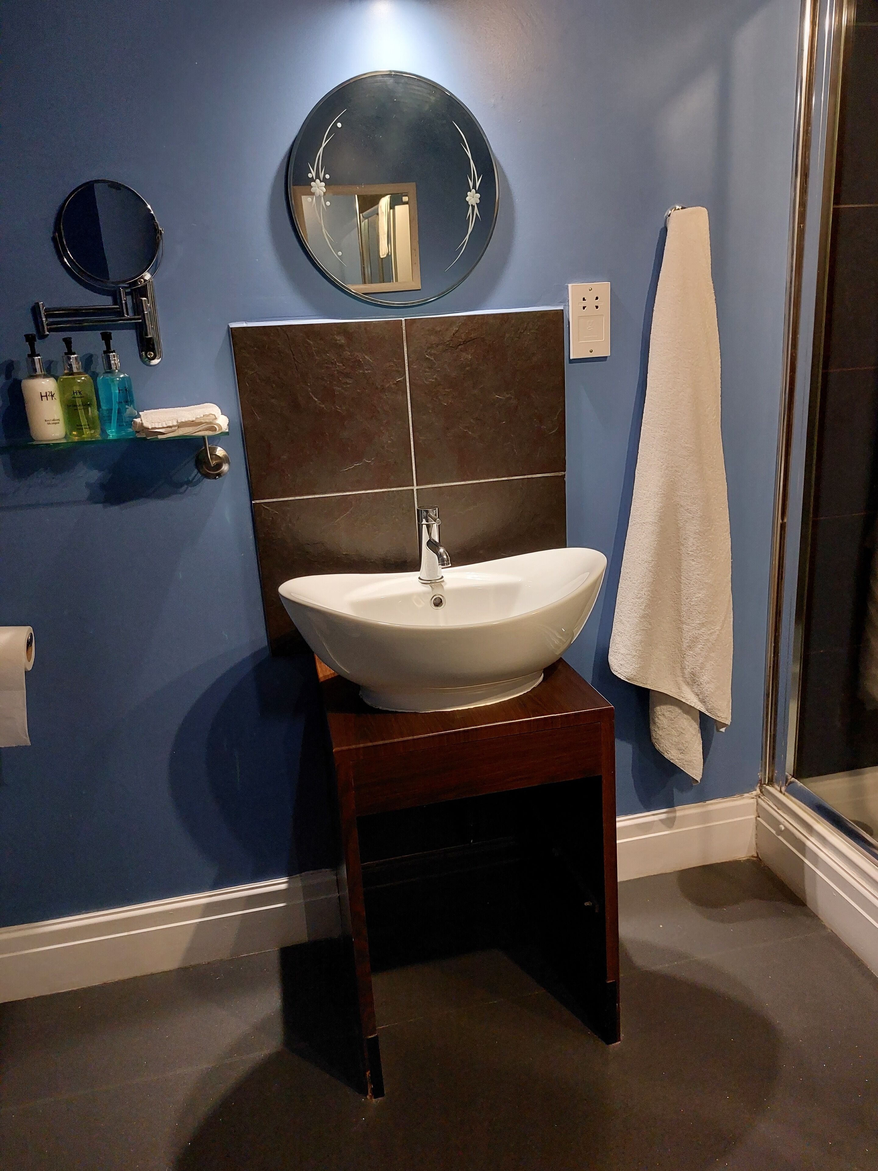 Une salle de bain avec un lavabo blanc, un miroir et une serviette accrochée au mur.