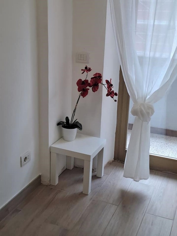 Una habitación con un banco blanco, una planta en maceta y una cortina translúcida.