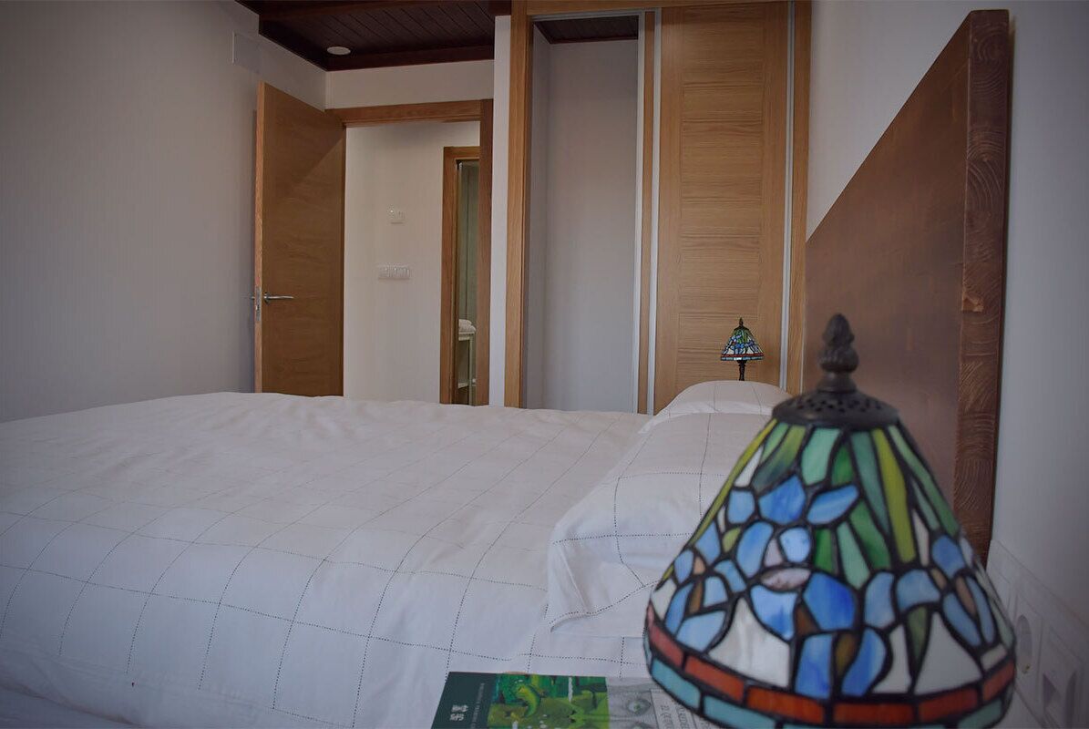 Une chambre à coucher avec un lit, une porte en bois et une lampe en vitrail.