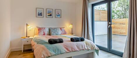 Une chambre à coucher avec un lit, des lampes de chevet, une fenêtre et une vue sur l’extérieur.