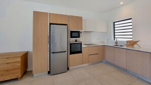 Uma cozinha moderna com geladeira embutida, forno, micro-ondas e um armário de madeira.