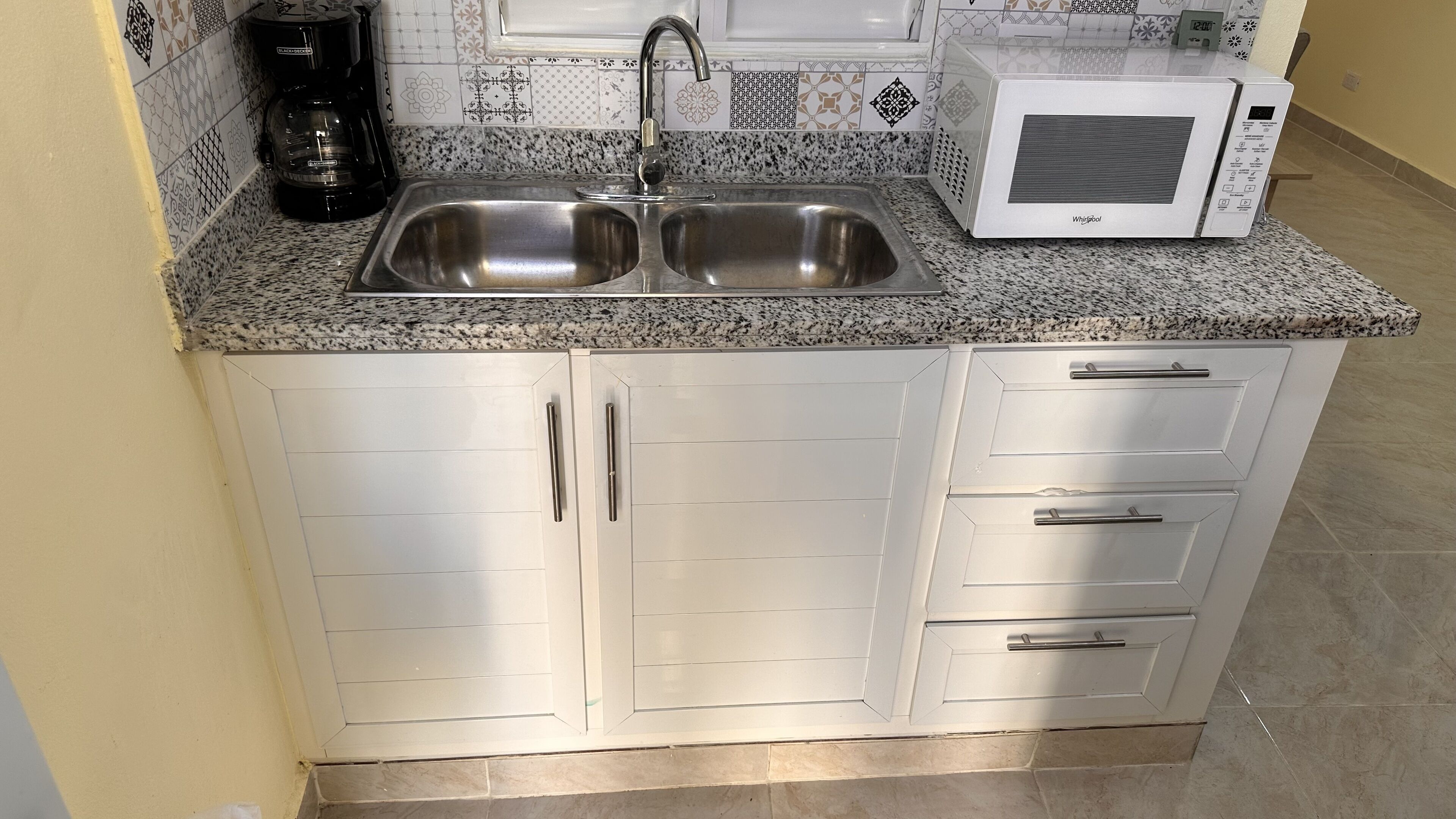 A kitchen with a double sink, a coffee maker, and a microwave.