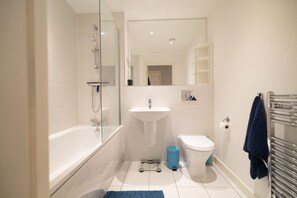 A modern bathroom with a bathtub, sink, toilet, and a mirror.