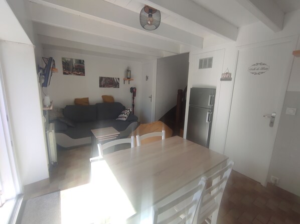 A living room with a sofa, coffee table, and a refrigerator. - Les Petits Embruns, Moins de 2 km des Plages (Moëlan-sur-Mer)