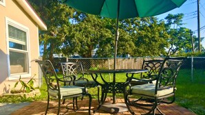 A patio with a table and chairs, surrounded by a brick floor and greenery. - Tropical Suite with Garden near Beaches & Nature in Melbourne (Melbourne)