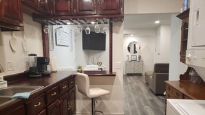 A kitchen with wooden cabinets, a bar stool, a coffee maker, and a blender. - Newly renovated private basement appartment. 2 bedrooms, 2 bathroom w/jetted tub (Brighton)