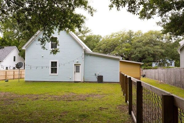 Stroll through the charming backyard, complete with a grassy lawn and a wooden fence, surrounded by trees.