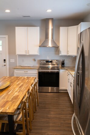 Enjoy cooking in this well-lit kitchen with a central island, white cabinetry, and stainless steel appliances.