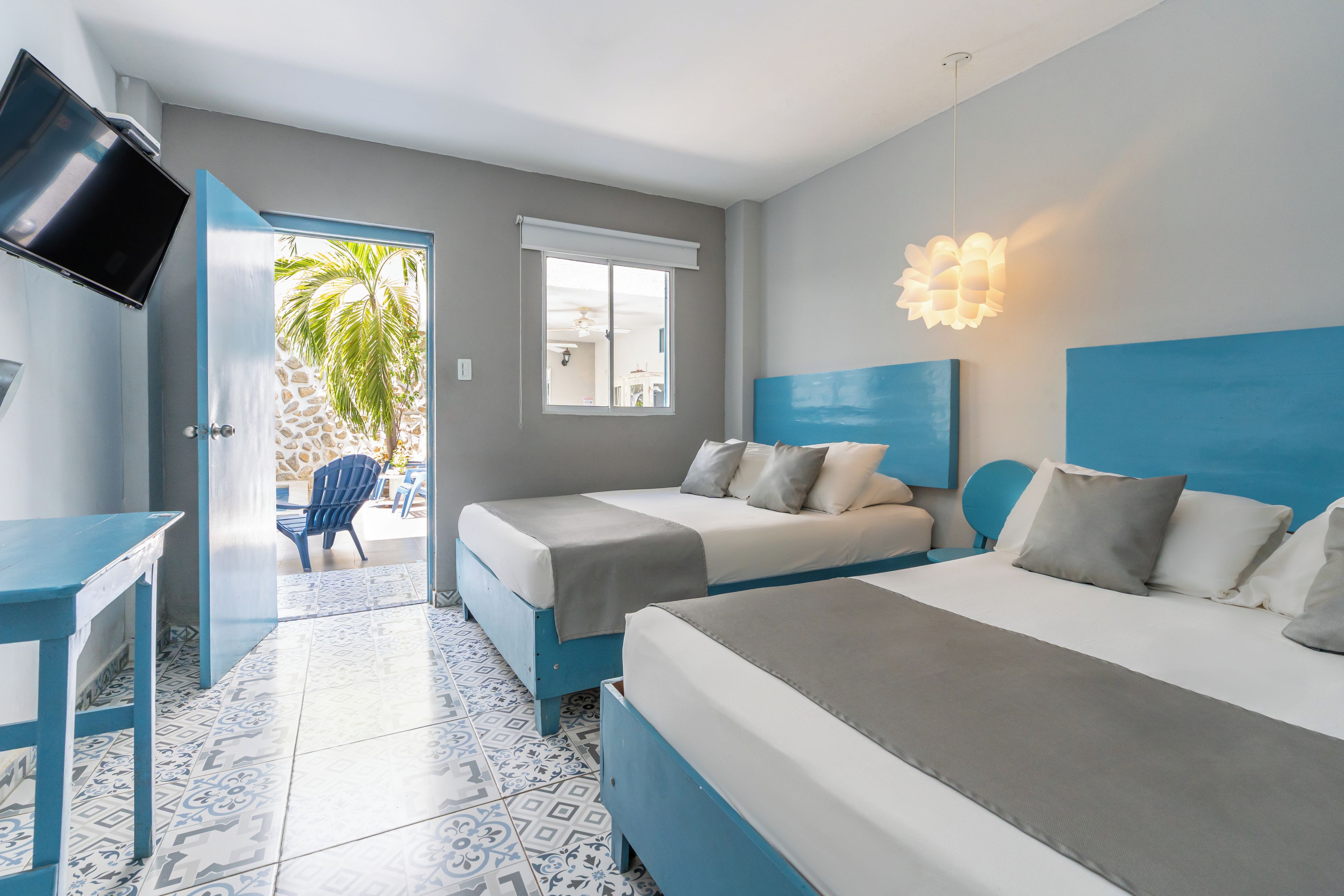 Habitación de hotel con dos camas, televisión, escritorio y vistas al exterior.