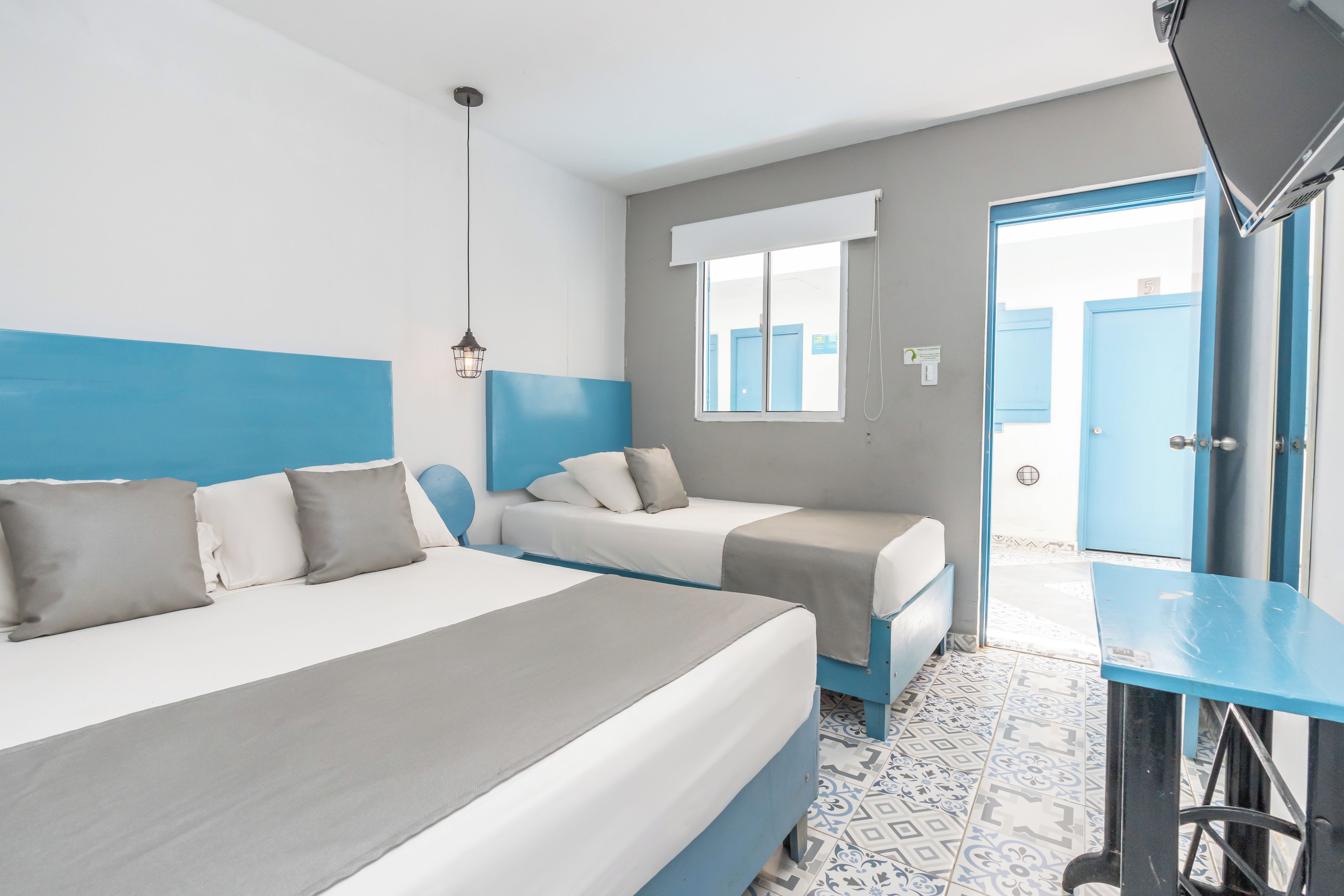 A hotel room with two beds, a desk, and a window.
