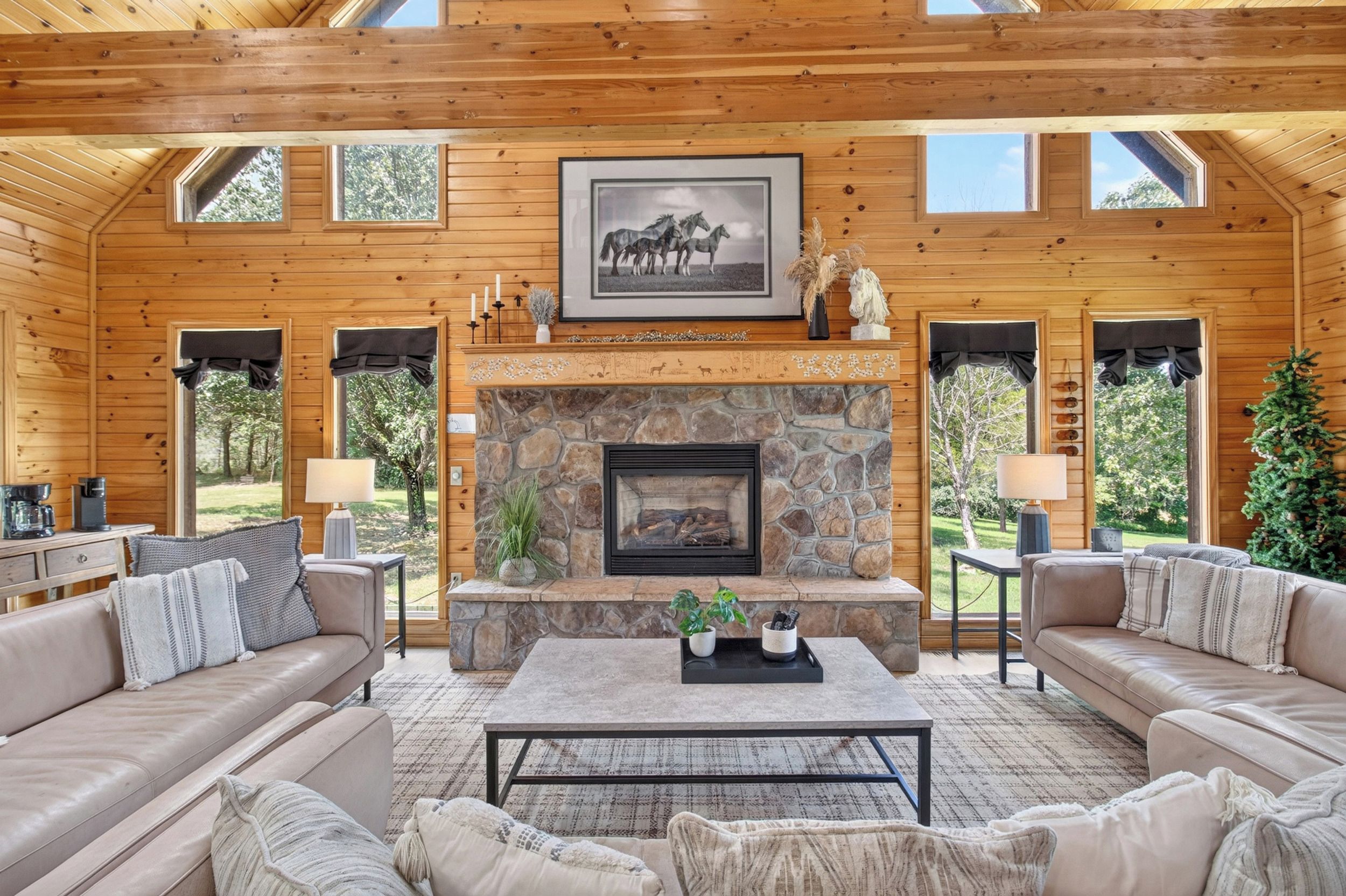 A spacious living room with a stone fireplace, leather sofas, and a coffee table.