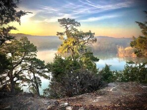 A serene lakeside view with dense trees and a clear sky. - LakeFront - 15’ Theater Screen - Kayaks - 4Acres -FirePit (Eagle Rock)