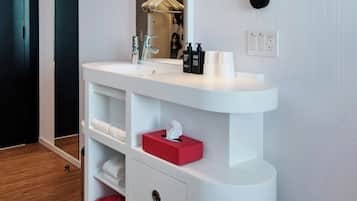 Une salle de bain moderne avec un meuble-lavabo blanc, un miroir, une lampe noire fixée au mur et un banc rouge.
