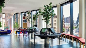 A modern interior with large windows, seating areas, and tables with laptops.