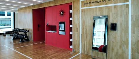 A gym with wooden flooring, red walls, and a mirror on the wall.