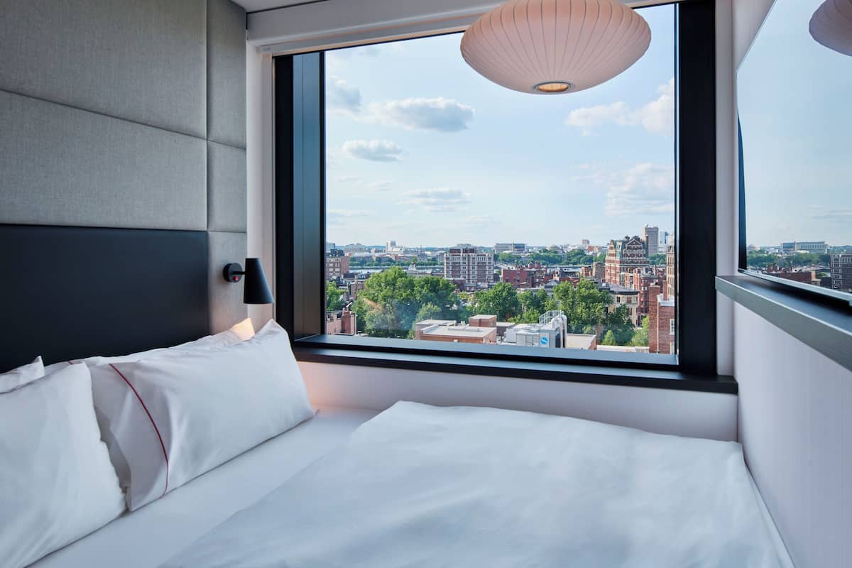 A modern hotel room with a large window offering a city view.