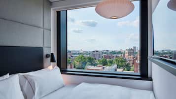 Habitación de hotel moderna con un ventanal grande que ofrece vistas de la ciudad.