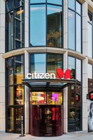 The exterior of a hotel with a glass facade, a prominent 'Citizen Hotel' sign, and a revolving door entrance.