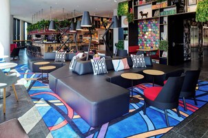 A modern lounge area with sofas, round tables, and a colorful carpet.