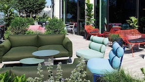 An outdoor seating area with a green sofa, a blue chair, and red chairs.