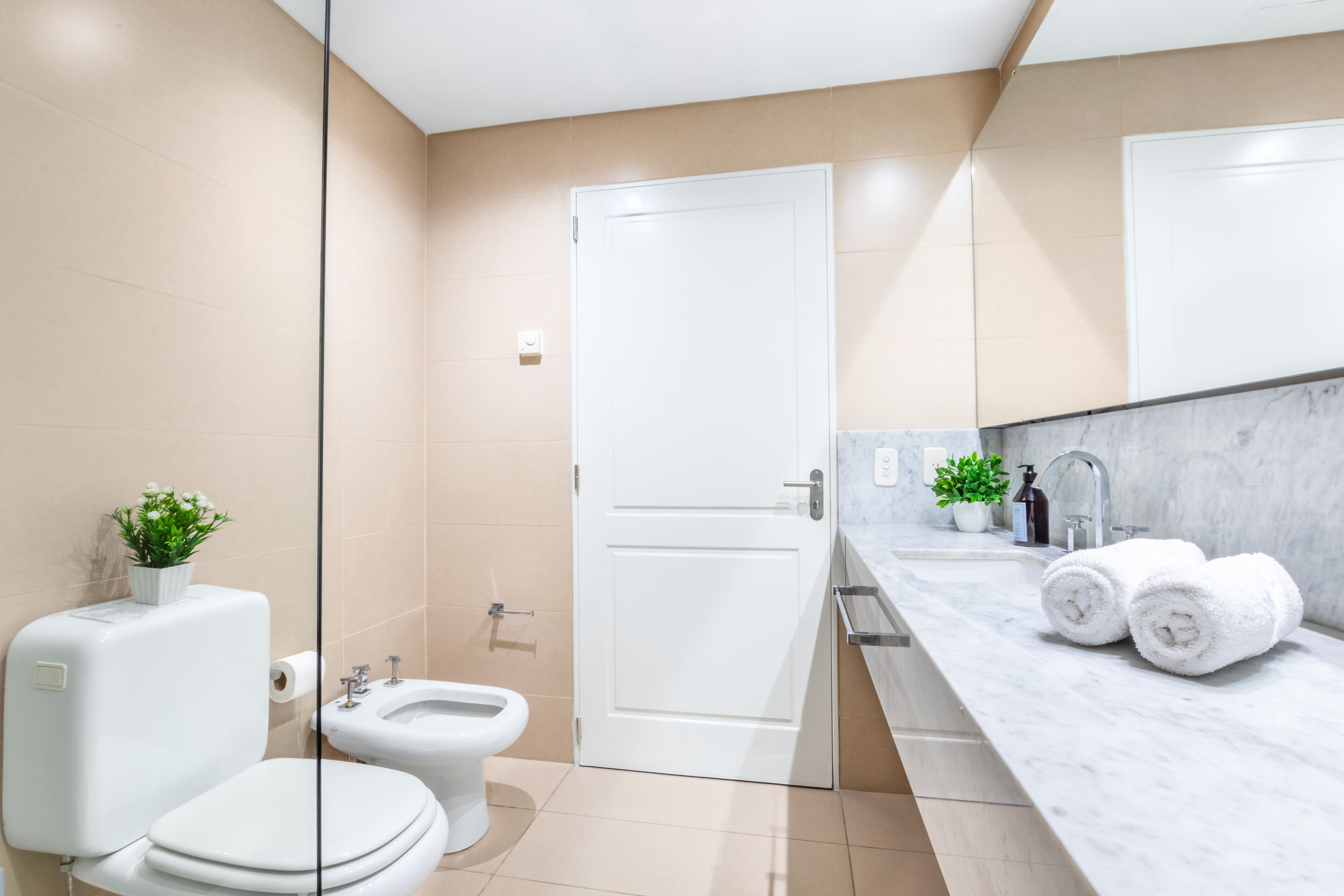 Un baño moderno con inodoro, bidé y encimera de mármol con toallas.
