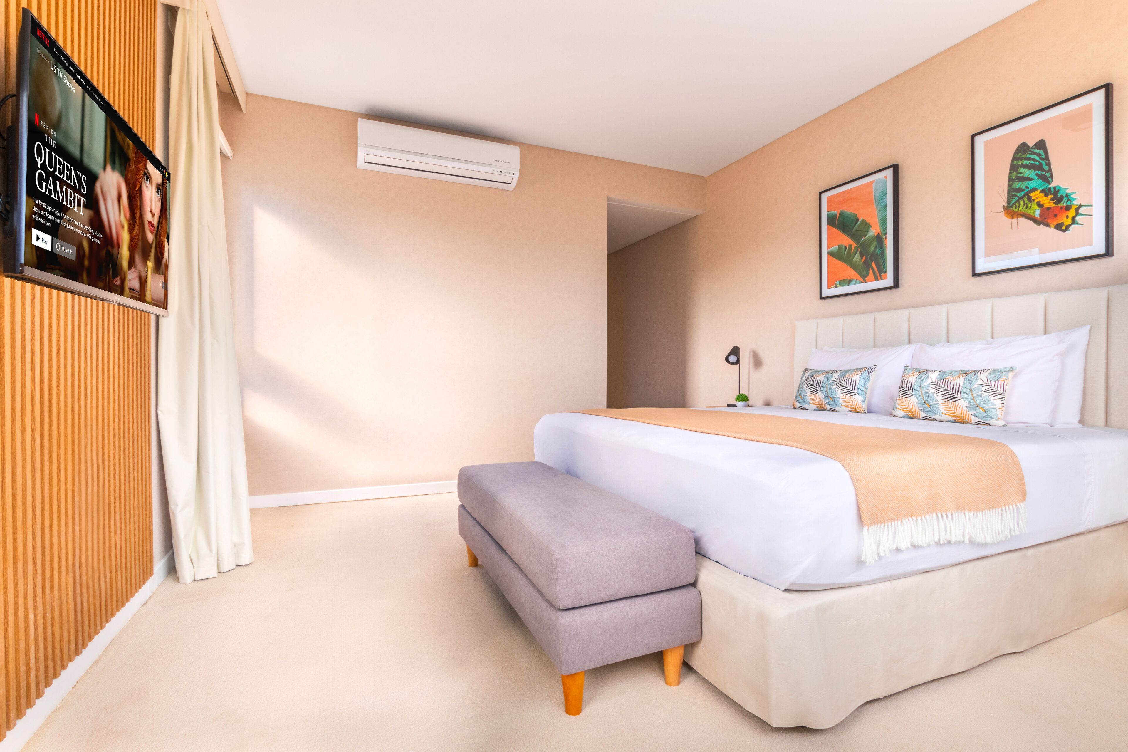 Una camera da letto con un letto, una panca, una TV e opere d'arte alle pareti.