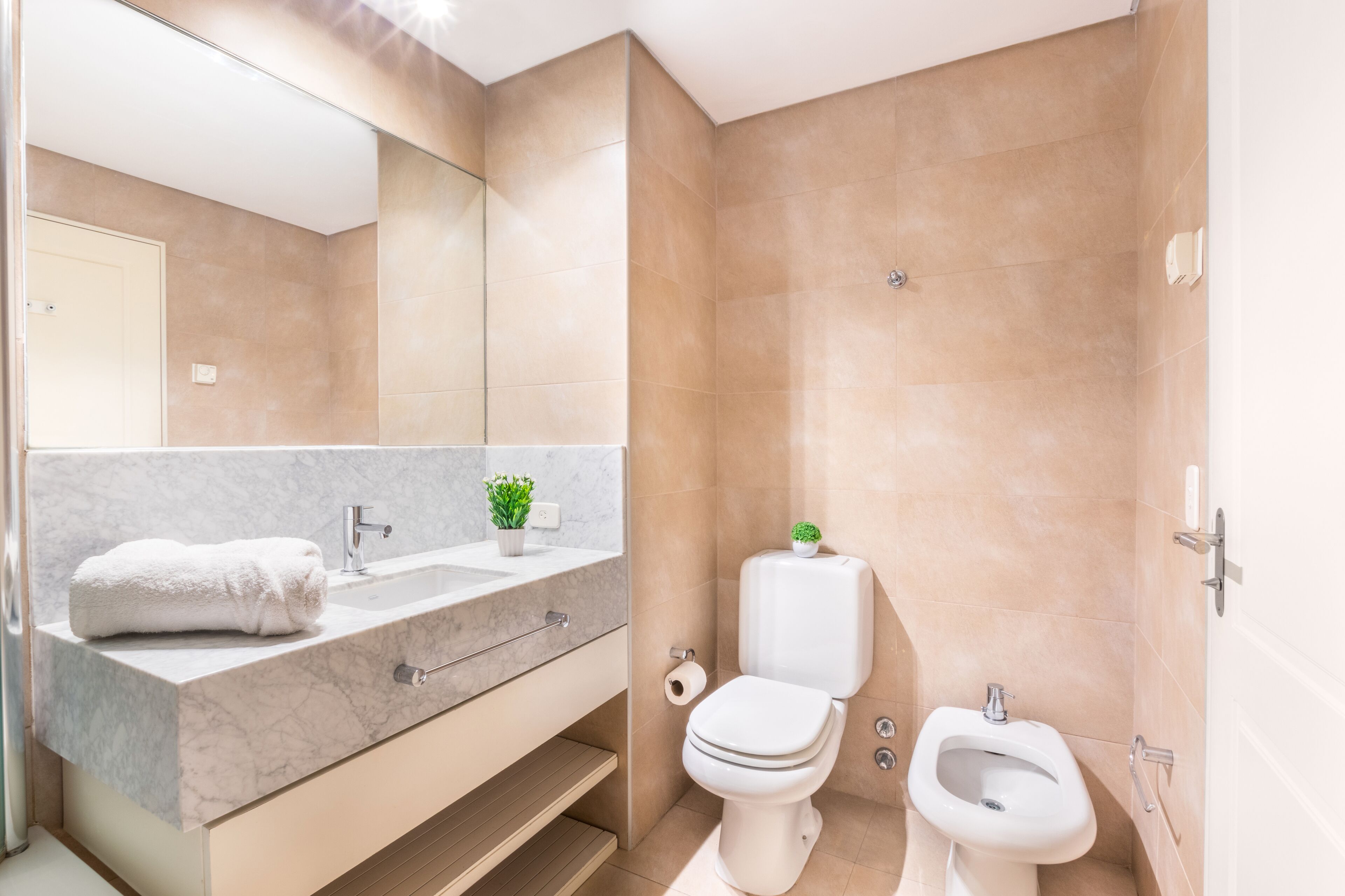 Un baño moderno con tocador de mármol, inodoro, bidé y un espejo grande.