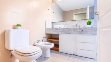 Un bagno moderno con toilette, bidet e mobili bianchi.