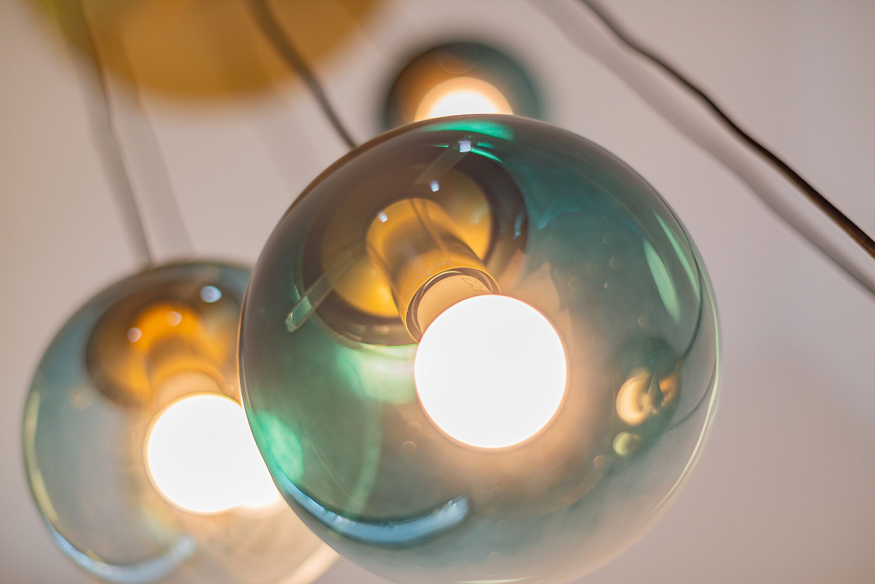 Gros plan sur des suspensions sphériques en verre, diffusant une lumière chaleureuse.