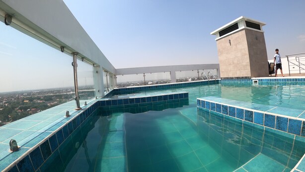A rooftop infinity pool with clear blue tiles and a city view.