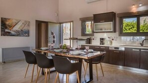 Una cocina moderna con armarios de madera oscura, una isla grande con sillas y una mesa de comedor para cuatro.