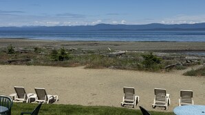 Une plage avec des chaises longues et une vue sur l’océan et les montagnes.