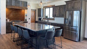 A modern kitchen with a large island, bar stools, stainless steel appliances, and wooden cabinetry. - Stunning view of the Tetons - Tetonia Base Camp  (Tetonia)