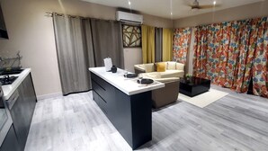 A modern kitchen with a central island, a dining area with a sofa, and a living space with a TV. - TIES LUX VILLA COUPLE SUITES (La Fargue)