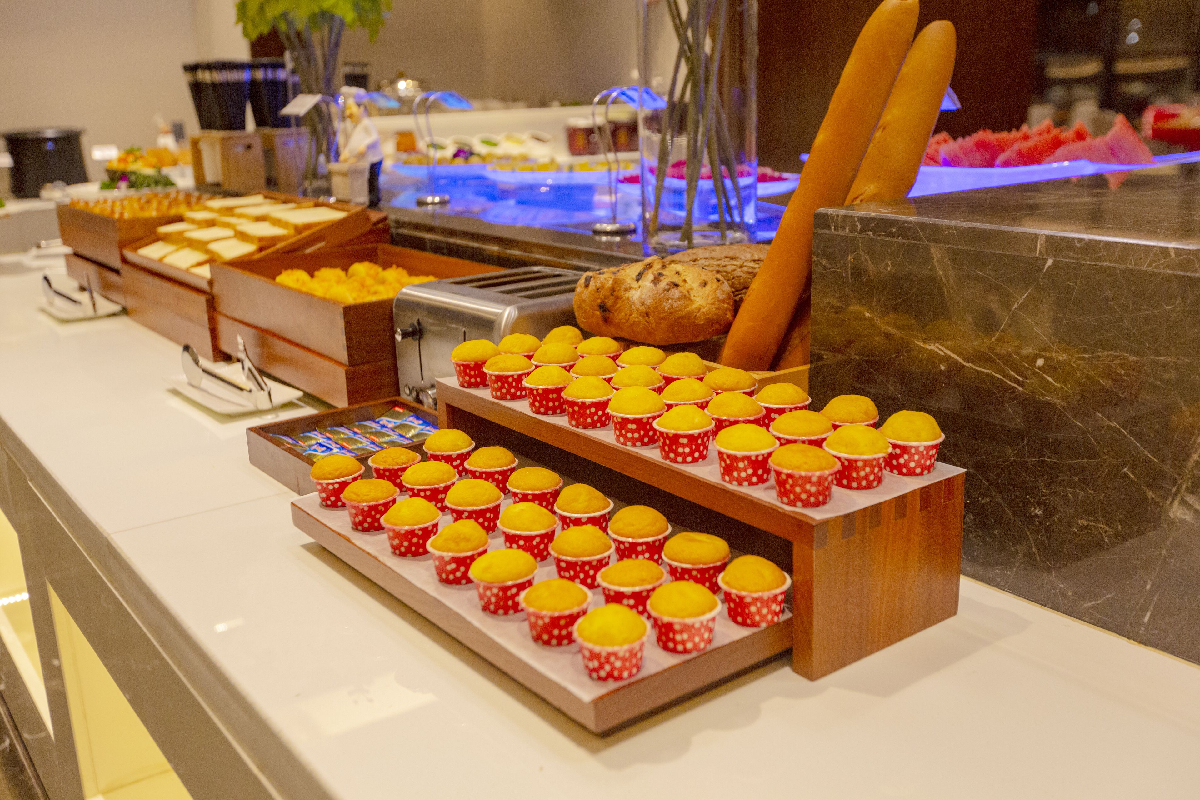 Un bufé con diferentes opciones de comida, incluyendo cupcakes, pan y una barra de sushi.