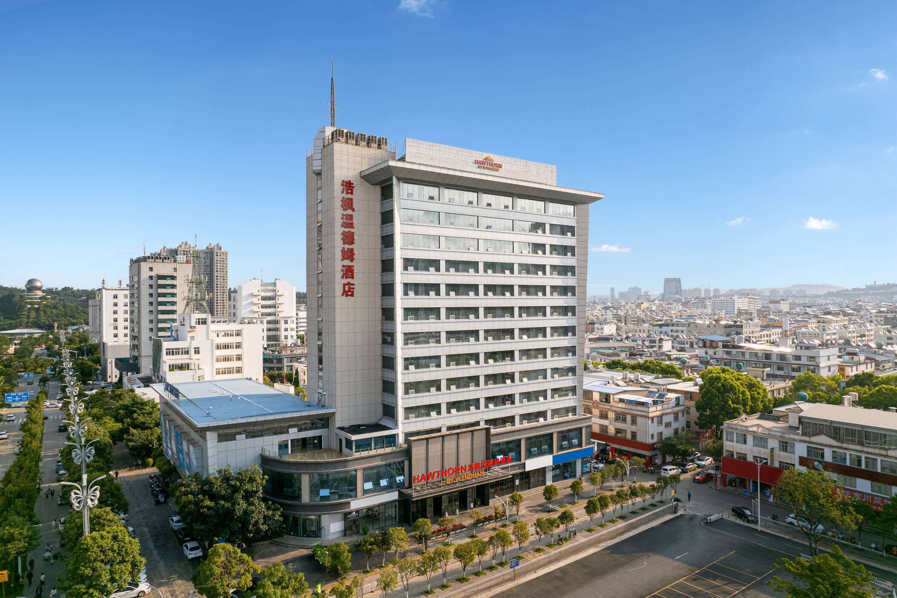 A multi-story hotel with a modern design, featuring a prominent vertical sign and a flat roof.