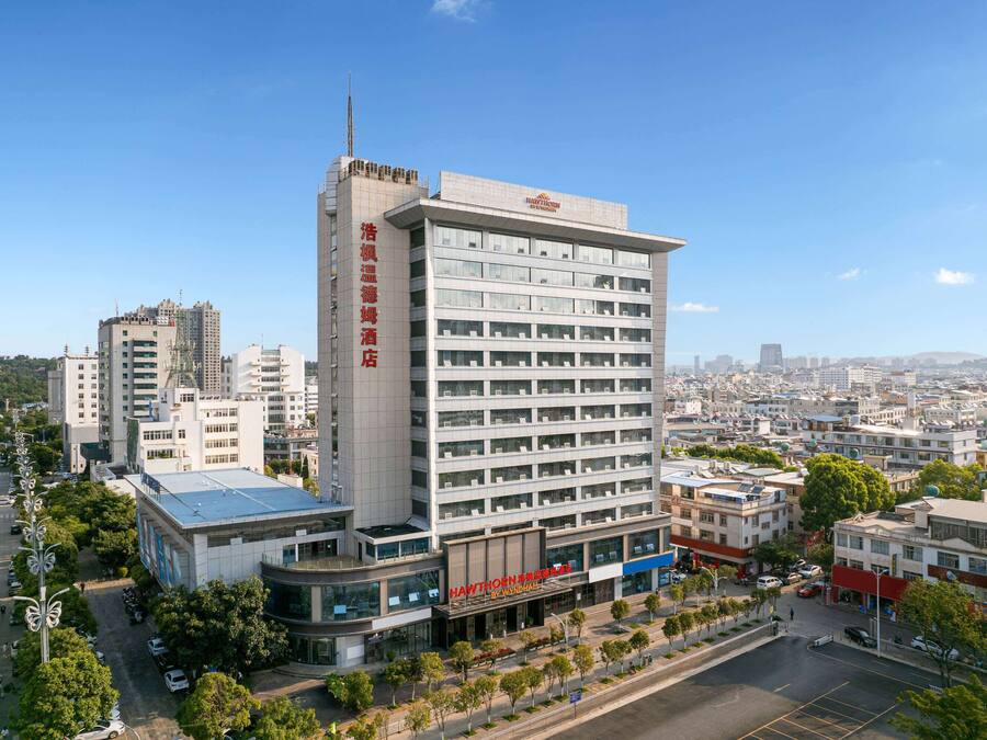 Un hotel de varios pisos con diseño moderno, que destaca un cartel vertical y un techo plano.