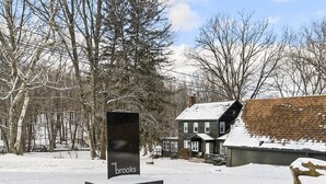 A snow-covered landscape with a house and a sign that reads "the brooks".
