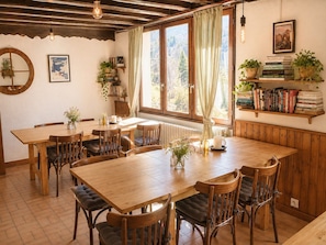 A cozy dining area with a wooden table and chairs, surrounded by bookshelves and potted plants. - Hotel Au Bon Accueil (Les Deux Alpes)