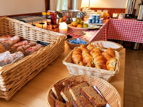 A buffet table with various breads, pastries, and fruits. - Hotel Au Bon Accueil (Les Deux Alpes)