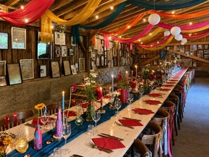 A long dining table set for a meal with a wooden backdrop and framed pictures. - Hotel Au Bon Accueil (Les Deux Alpes)