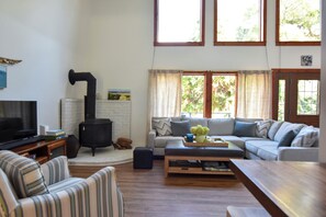 A living room with a fireplace, sofa, and television. - Walk to the beach from this cozy birder cottage! 3beds, 2ba (Cape May Point)