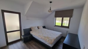 Ein Schlafzimmer mit Bett, Kommode, Fenster mit Aussicht und Tür.
