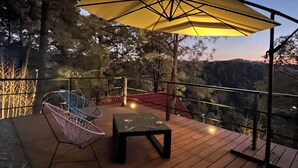 A wooden deck with a table and chairs, an umbrella, and a railing overlooking a mountainous landscape. - Mi Refugio Nordico Pequena Cabana (Donato Guerra)